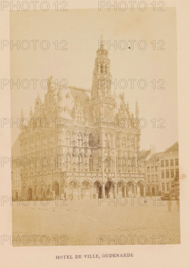 Hotel de ville, Oudenarde, photograph, page, Oudenaarde, c. 1856 - in or before 1866, photographer, paper, albumen print, albumendruk, height 158 mm x width 112 mm, arcade, architecture, Stadhuis van Oudenaarde, A large ornate stone building with Gothic architectural details fills the left and center of the image, featuring pointed arches at ground level, rows of tall narrow windows, decorative tracery, pinnacles, and sculptural ornamentation; a tall central tower with an elaborate spire rises above the roofline; adjacent buildings with simpler facades and pitched roofs appear to the right; an open cobblestone square occupies the foreground; a lone figure stands near the building entrance and a blurred person is visible near the right edge; the photograph has a faded, sepia-toned appearance.