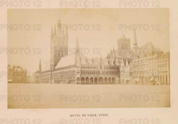 Hotel de ville, Ypres, photograph, page, c. 1856 - in or before 1866, photographer, paper, albumen print, height 110 mm x width 178 mm, square, circus, façade (of house or building), Cloth Hall, A wide sepia-toned photograph of an ornate town square dominated by a large Gothic-style building with tall spires, pointed arches, and a steeply pitched roof, adjoining a row of multi-story buildings with gabled facades, dormer windows, and a narrow tower with a spire; the foreground shows a broad open paved area, and the buildings display repeated arched arcades, decorative stonework, and a variety of window shapes and rooflines.