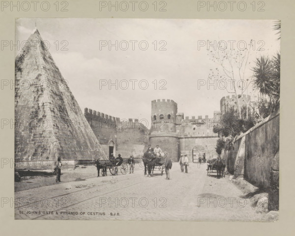 St John's gate & pyramid of Cestius, page, photomechanical print, photographer: Samuel J. Beckett, Rome, printmaker: Samuel J. Beckett (possibly), c. 1890 - c. 1900, Samuel J. Beckett, photographer, printmaker, paper, collotype, photoprint, height 153 mm x width 198 mm, pyramid (marking grave), gate, entrance, Porta San Paolo, Pyramid of Cestius, A wide street scene in monochrome shows a large stone pyramid on the left and a fortified stone gate with rounded towers and crenellations toward the center and right, with a high wall extending across the scene; several horse-drawn carriages and horses occupy the roadway and people in period clothing stand and walk among them; a tall thin tree with sparse branches rises near the right-side tower and spiky palm-like plants grow along the right wall; cobbled pavement and faint tram tracks run through the foreground and a few individuals stand near the pyramid base and along the walls.