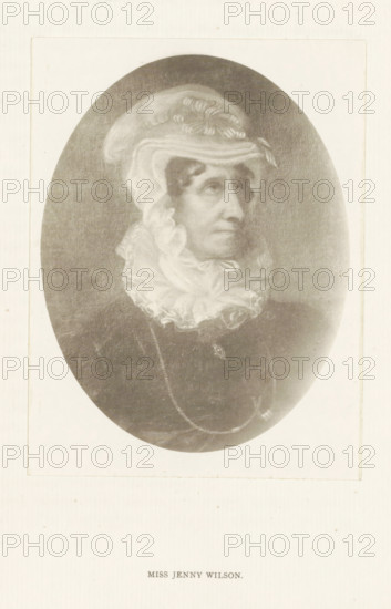 Miss Jenny Wilson, photograph, reproduction, page, after painting by anonymous, c. 1886 - in or before 1896, photographer, paper, platinum process, height 130 mm x width 98 mm, Person, Jenny Wilson, historical persons - BB - woman, An oval portrait of an older woman shown from the shoulders up, wearing a light-colored, ruffled head covering and a high, frilled neckpiece; her face is turned slightly to the side with a neutral expression, and she has pronounced cheekbones and a long nose. Her dark clothing contrasts with the pale fabric around her head and neck, and a delicate chain with a small pendant is visible over the front of her garment. The image is set against a light rectangular background with a narrow border.