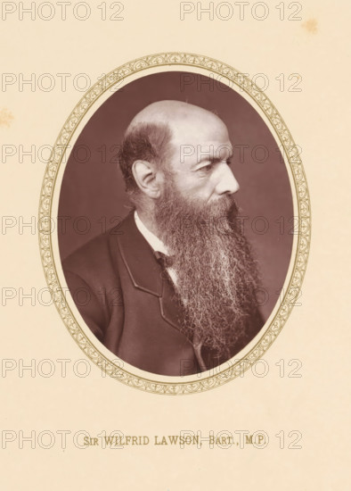 Sir Wilfrid Lawson, Bart., MP, page, photomechanical print, c. 1875 - c. 1880, photographer, printmaker, paper, Woodburytype, height 110 mm x width 87 mm, Person, Wilfrid Lawson, politician, eg party leader, An oval sepia photograph centered on a beige page shows an older man in profile facing right with a high forehead and a long, full beard extending down over his chest, wearing a dark jacket and a light collar; the oval is bordered by a decorative patterned frame and the background inside the oval is a darker plain tone.