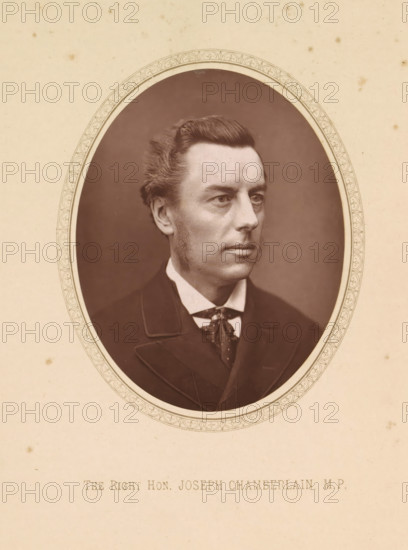 Portrait of Joseph Chamberlain, The right hon. Joseph Chamberlain, MP, page, photomechanical print, c. 1874 - in or before 1884, photographer, printmaker, paper, Woodburytype, height 111 mm x width 87 mm, Person, Joseph Chamberlain, politician, eg party leader, A sepia-toned oval portrait of a clean-shaven man with sideburns and neatly combed hair, shown from the shoulders up and turned slightly to his left, wearing a dark suit jacket, a white shirt with a high collar, and a patterned cravat, all set against a plain dark background and mounted on a textured light-colored mat with a decorative oval border.