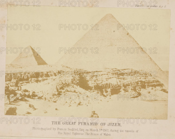 The great pyramid of Jiza, photograph, page, inscription: 'Photographed by, Prince of Wales', number: 'Plate 1.', photographer: Francis Bedford, Giza, 1862-03-05, North Africa, paper, albumen print, albumendruk, height 137 mm x width 92 mm, Photo on frontispiece., Egyptian pyramids (Wonder of the World), Pyramid of Cheops, A faded sepia photograph showing a desert scene with two large pyramidal stone structures rising from a rocky, uneven foreground; the larger pyramid is on the right and the smaller pyramid is to the left with a triangular darker face visible, while the foreground displays scattered stones, ledges, and eroded rock formations under a pale sky.