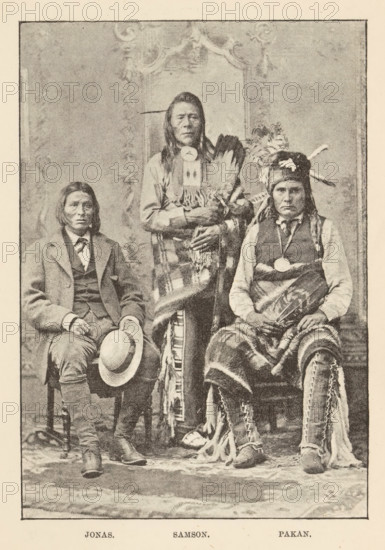 Portrait of three Cree or Saulteaux men from Canada, Jonas. Samson. Pakan, page, photomechanical print, Canada, c. 1882 - in or before 1892, North America, paper, autotypie, height 141 mm x width 98 mm, adult man, anonymous historical persons depicted in a group, in a group-portrait, human races, peoples, nationalities, Native peoples of the Americas, original inhabitants of North America, A sepia-toned photograph of three seated and standing men posed against a decorative backdrop, each wearing distinct clothing and accessories; the left figure sits holding a brimmed hat in his lap and wears a suit jacket, vest, tie, and straight hair parted in the middle, the central figure stands slightly behind the others wearing long hair, a fringed garment draped over the shoulders, and holding a fan of feathers, and the right figure sits wearing a fur hat adorned with feathers, a vest over a shirt, a circular chest ornament, and a patterned blanket wrapped around the lower body with hands restin...