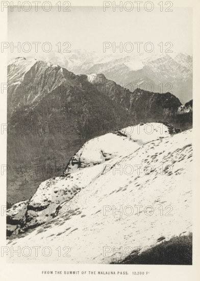 View from the summit of the Malana pass, Himachal Pradesh, India, page, photomechanical print, caption: 'FROM THE SUMMIT OF THE MALAUNA PASS. 12, 200 Ft', photographer: Frederick Saint John Gore, Malana, c. 1890 - in or before 1895, printmaker, Parvati valley, paper, collotype, photoprint, height 179 mm x width 129 mm, mountain-range, snow peaks, A snowy mountain slope fills the foreground with patches of exposed rock and sparse vegetation, leading to rounded snow-covered ledges and rocky outcrops; behind them a darker, steep ridgeline rises with craggy cliffs and forested sections, and in the distant background a range of rugged, snow-dusted peaks recedes under a pale sky.