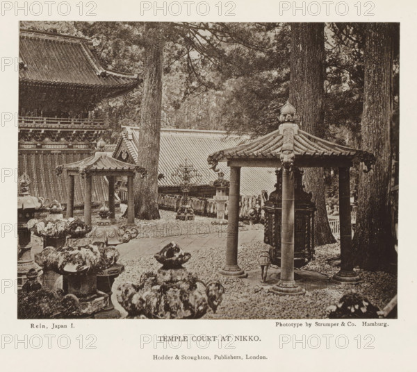 Temple court at Nikko, page, photomechanical print, Nikko, printmaker: Strumper & Co, Hamburg (city), publisher: Hodder & Stoughton, London, c. 1874 - in or before 1884, photographer, Kanto, paper, collotype, photoprint, height 117 mm x width 151 mm, facade of inner court, temple, shrine, Shinto, A sepia-toned photograph showing an outdoor scene with traditional East Asian temple architecture and stone lanterns among tall trees, featuring a tiled pavilion roof supported by cylindrical columns in the foreground and ornate carved details on roof edges and lantern tops, uneven stone and gravel ground with scattered rocks and ornamental bases, large tree trunks rising behind the structures, a larger building with a steep tiled roof and decorative eaves partially visible in the background, and various sculptural elements and carved wooden or stone fixtures arranged throughout the courtyard.