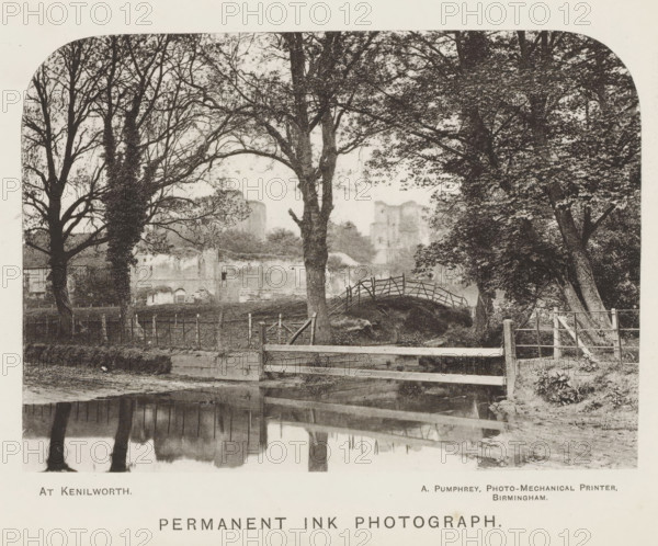 At Kenilworth, page, photomechanical print, inscription: 'Permanent ink photograph', Kenilworth, printmaker: A. Pumphrey, Birmingham, c. 1868 - in or before 1878, photographer, paper, collotype, photoprint, height 100 mm x width 140 mm, landscape with bridge, viaduct or aqueduct, landscape with tower or castle, A sepia-toned landscape showing a row of large trees with bare and leafy branches framing a view of distant ruined stone structures, a small arched wooden footbridge over a grassy mound, a low wooden fence and gate in the foreground beside a calm reflective body of water that mirrors the trees, and a fenced area with posts and wire along the middle ground.