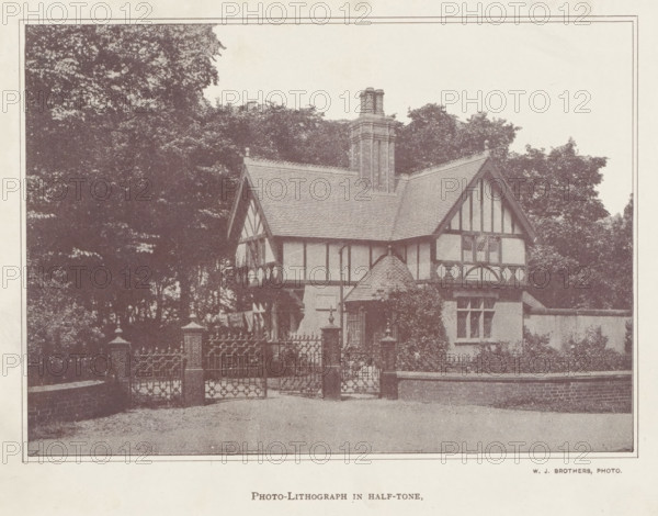 Exterior of a house, page, photomechanical print, photographer: A. Brothers & Co., c. 1889 - in or before 1899, paper, autotype, photo-lithograph in half-tone, height 111 mm x width 158 mm, housing, facade (of house or building), A sepia-toned image of a half-timbered house with steep gabled roofs and a tall central chimney, partially obscured by trees behind and to the side, a fenced entrance with ornamental metal gates and stone pillars in front, a low brick wall extending along the foreground, and windows and decorative timber patterns visible on the house facade.