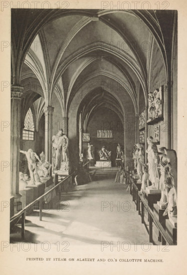 Image gallery, page, photomechanical print, printmaker: Alauzet & Co. (possibly), c. 1877 - in or before 1887, photographer, printer (person), paper, collotype, printed by steam, height 143 mm x width 102 mm, gallery of sculptures, exterior, representation of a building, A long vaulted interior with pointed ribbed arches and tall columns framing a central aisle lined on both sides with sculpted figures on pedestals and relief panels mounted on the walls, sunlight casting shadows across the floor from a tall arched window on the left, a bench or railing running along the aisle edges, and distant statues and a raised platform visible at the far end.