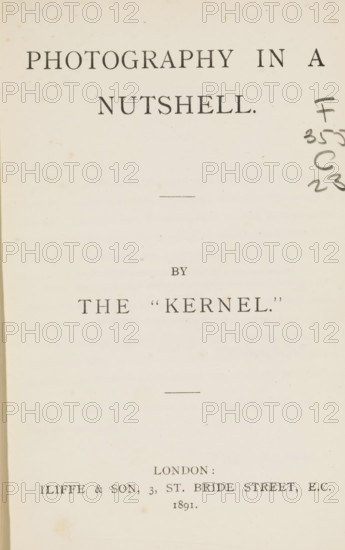 Photography in a nutshell, book, publisher: Iliffe & Son, London, 1891, textile materials, pasteboard, paper, linen (material), autotype, printing, Woodburygravure, kallitype, aututypie, Woodburygravure and callitype, height 189 mm x width 130 mm x thickness 20 mm, A pale, aged page with dark printed lines of large serif lettering across the top and center, a short horizontal rule near the upper middle and another near the lower middle, faint brown foxing spots scattered across the background, a column of dark handwritten ink marks along the right edge, and squared margins showing the inner binding edge on the left.