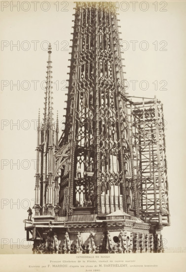 Copper spire for the roof turret of Notre-Dame in Rouen with workmen inside, Cathédrale de Rouen Premier Clocheton de la Flèche, travail en cuivre tortureé, photograph, page, inscription: 'Exécutés dans les ateliers de F. Marrou, d'après les plans de M. Barthélemy, architect honoraire', name: 'Witz & cie Phot. Rouen', photographer: Witz et Cie., Rouen, 1881-08, Witz et Cie., photographer, paper, albumen print, height 273 mm x width 210 mm, building-site, parts of church exterior and annexes: steeple, Rouen Cathedral, A tall ornate Gothic spire under construction fills the frame, showing intricate lattice-like stone or metal tracery with repeating pointed arches and circular openings, slender pinnacles topped with finials, and decorative crockets along the edges; scaffolding and wooden support structures flank one side of the spire, and a platform near the base holds several workers standing and sitting; the lower portion reveals a decorated cornice with small sculptural elements and a ...