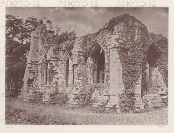 Furness Abbey_the guest chapel, Chapel at the ruins of Furness Abbey, page, photomechanical print, photographer: Alfred Pettitt, Furness Abbey, Keswick, c. 1870 - in or before 1880, paper, heliotype, height 125 mm x width 173 mm, ruin of church, monastery, parts of church exterior and annexes: chapel - QQ - small church, chapel, Cumbria, A sepia-toned photograph of a ruined stone building partially covered in climbing vegetation, showing several tall arched window openings with sections of broken masonry and stone buttresses, metal bars set into some openings, rough rubble and overgrown plants at the base, a grassy foreground, and large trees visible behind the structure beneath a cloudy sky.