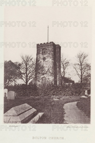 View of the Holy Trinity Church in Bolton-le-Sands, Bolton church, page, photomechanical print, photographer: Alex Rivington, Bolton-le-Sands, London, c. 1870 - in or before 1880, paper, heliotype, height 155 mm x width 114 mm, church (exterior), parts of church exterior and annexes: tower, A stone church tower rises from a grassy churchyard, its battlemented top and narrow vertical flagpole visible against a pale sky, with a small arched window and circular opening on the tower face; leafless trees stand around the tower, their branches silhouetted, and hedges border the base of the building; in the foreground are stone tombs and a winding dirt path through the grass leading toward the church.