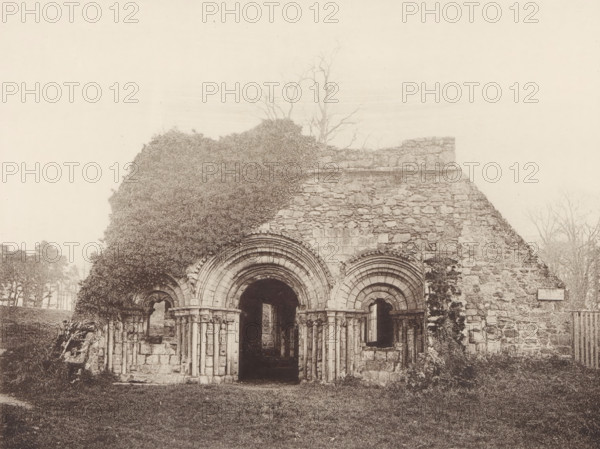 Chapter House, Haughmond Abbey, View of the ruins of the chapter house of Haughmond Abbey, page, photomechanical print, photographer: J. Laing, cliché maker: anonymous, c. 1867 - in or before 1877, Shrewsbury, paper, collotype, photoprint, height 151 mm x width 194 mm, ruin of church, monastery, A weathered stone building facade with rounded arched doorways and decorative concentric arch moldings, partially covered by climbing vegetation that obscures part of the left side, stands amid a grassy foreground; the stonework shows rough, irregular blocks and remnants of columns flanking the arches, while bare tree branches rise behind and above the structure against a pale sky.