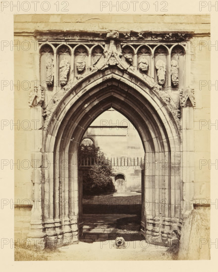 Portal of the ruins of Melrose Abbey, photograph, page, title: 'Richly molded Gothic portal', number: '(No. 3.)', inscription: 'Under No. 2. At point of the Arch, a Shield with the Royal Arms of Scotland, and a remarkable figure of John the Baptist with eye directed to the Saviour, and Inscription on Scroll 'Ecce Filius Dei.'', photographer: WJ Pringle, Melrose Abbey, c. 1860 - in or before 1870, Melrose (Scotland), paper, albumen print, height 165 mm x width 131 mm, ruin of church, monastery, parts of church exterior and annexes: portal, A stone arched doorway with layered pointed arches fills the frame, flanked by carved columns and ornate stonework, with a row of small sculpted figures set into niches above the arch; beyond the arch a gated opening reveals a courtyard with a distant arched doorway and trees, and a small long-haired dog sits on the ground in the foreground.