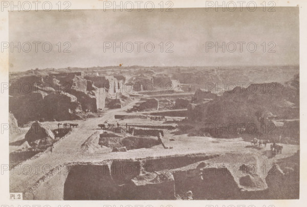 View of a diamond mine in South Africa, presumably near Kimberley, page, photomechanical print, number: 'Pl. 2', photographer: Gray Brothers (possibly), South Africa, c. 1870 - in or before 1880, paper, collotype, photogravure, height 124 mm x width 186 mm, Print in rear image section., mine, Kimberley, A wide, desaturated landscape showing layered, rectangular excavations and steep earthen walls stretching into the distance under a pale sky, with rough dirt roads winding between the cut terraces, scattered large rock formations, several horse-drawn carts and small groups of people on the roads, and distant low ridges along the horizon.