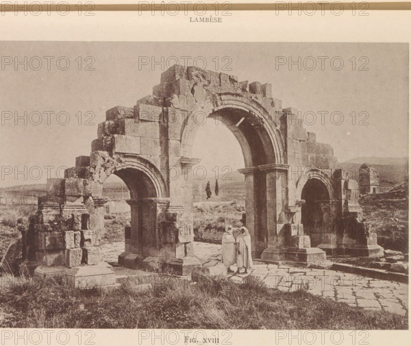 Arc de Septime Sévére, View of the arch of Septimius Severus at Lambaesis in Algeria, page, photomechanical print, number: 'Fig. XVIII', Algeria, maker: Berthaud Frères, France, c. 1884 - in or before 1894, photographer, North Africa, paper, collotype, photoprint, height 105 mm x width 151 mm, Print after page 24., triumphal arch, Lambaesis, A sepia-toned photograph showing a partially ruined stone arch structure with three large arches and weathered block masonry, standing on a paved and grassy ground, with two figures wearing long robes and head coverings standing beneath the central arch, and a distant landscape with low hills visible through and beyond the arches.