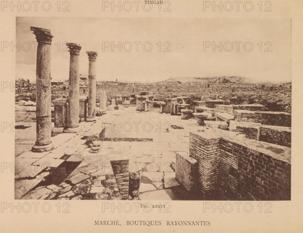 Marché, boutiques rayonnantes, View of Roman ruins of a market and shops in Timgad, page, photomechanical print, number: 'Fig. XXXVI', Timgad, maker: Berthaud Frères, France, c. 1884 - in or before 1894, photographer, North Africa, paper, collotype, photoprint, height 105 mm x width 159 mm, market-hall, landscape with ruins, A wide sepia-toned view of an ancient stone site showing a paved foreground with irregular flagstones and scattered fragments, a row of tall weathered columns with decorative capitals along the left side, low brick and stone walls forming rectangular enclosures on the right, a few broken column drums and rectangular blocks placed near the columns, and a distant flat landscape beyond the ruins under a pale sky.