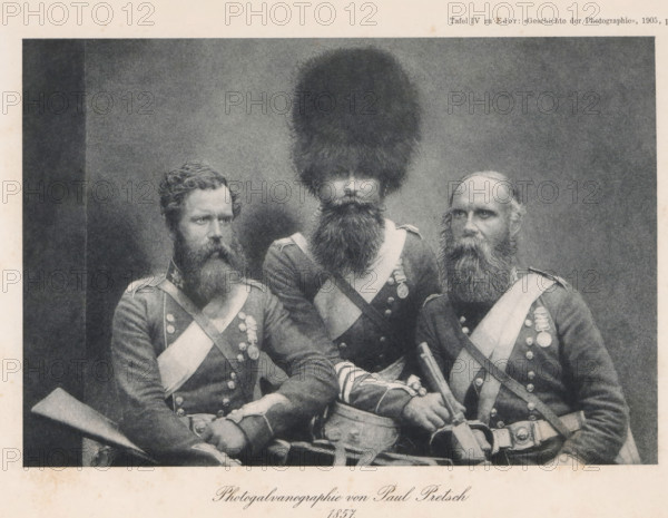 Portrait of three unknown men in uniform, page, photomechanical print, number: 'Tafel IV', photographer: Paul Pretsch, cliché maker: anonymous, c. 1900 - in or before 1905, paper, photogalvanography, height 123 mm x width 182 mm, Print after page 484., adult man, (military) uniforms, A black and white photograph of three uniformed men seated closely together, each wearing dark jackets with light diagonal sashes and rows of round buttons; the man in the center wears a very tall, furry hat and has a long full beard, the man on the left has curly hair and a thick beard and holds a long musket-like object across his lap, and the man on the right has a receding hairline with a long beard and rests one hand on a sword hilt and the other near a pouch at his waist; medals and decorative straps are visible on their chests and a drum or cylindrical object sits in front of the center figure.