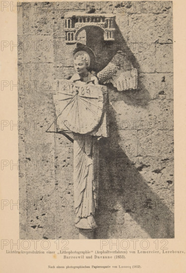Sculpture of an angel with a sundial on the facade of Chartres Cathedral, page, photomechanical print, inscription: 'Lichtdruckreproduktion, Davanne (1853)', number: 'Tafel IX', photographer: Henri Le Secq, Chartres, cliché maker: anonymous, c. 1900 - in or before 1905, paper, collotype, photoprint, height 176 mm x width 116 mm, Print after page 484., sculpture, church (exterior), sundial, Chartres Cathedral, A monochrome image of a stone wall with a sculpted figure mounted on it, showing a carved female bust with a detailed hair and facial features, draped clothing flowing down from the torso and a rounded base at the feet, the figure holds or is set behind a shield-like circular object with radiating lines, above the figure there is an architectural element resembling a small ornate canopy with column-like details, the stone surface shows textured blocks and shadowing on one side creating a dark triangular area beside the sculpture.