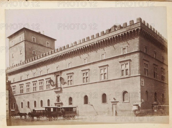 View of a façade of presumably a palace in Rome, photograph, page, Rome, c. 1850 - in or before 1860, photographer, paper, albumen print, height 98 mm x width 136 mm, façade (of house or building), A large multi-story stone building with a crenellated roofline and decorative corbels runs across the image, featuring rows of rectangular windows with simple frames and a series of arched ground-level openings with grilles. A taller square tower rises from the left portion of the building, with small windows and a plain cornice. Two enclosed horse-drawn carriages stand in front of the building on a cobbled street, each drawn by a team of horses. Architectural details include a small balcony with a doorway above it, a sculptural relief set into the facade, and various wall-mounted fixtures and shadows cast by the corbels. The photograph has a pale, slightly sepia tone.