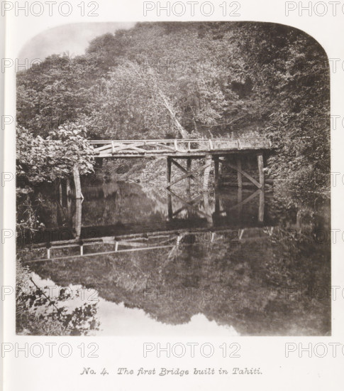 View of a bridge on Tahiti, The first Bridge built in Tahiti, page, photomechanical print, number: 'No. 4.', photographer: Henry Stuart-Wortley, Tahiti, cliché maker: Meisenbach's Autotype Company, printer (person): Meisenbach's Autotype Company, 1880, Meisenbach's Autotype Company, photographer, French Polynesia, paper, collotype, photoprint, height 138 mm x width 139 mm, bridge, A black and white photograph of a wooden bridge spanning a calm body of water, with wooden posts and cross-bracing supporting a plank deck and simple railing, surrounded by dense foliage and trees on both banks, one tree leaning toward the bridge, and the bridge and nearby vegetation reflected in the water below.