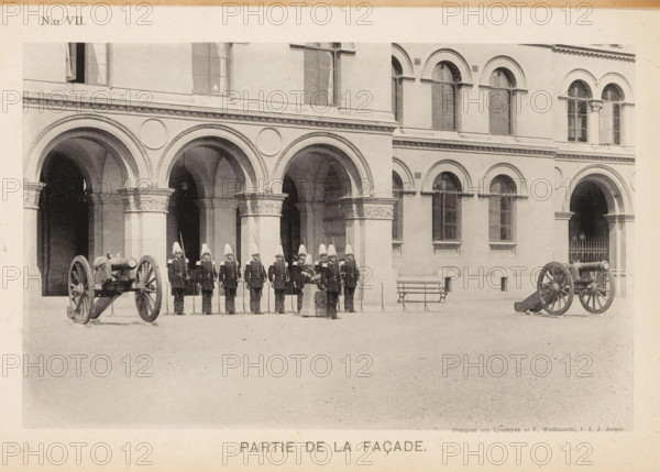 Façade of a barracks of the Svea livgarde in Stockholm with soldiers and cannons in front, Partie de la façade, page, photomechanical print, number: 'N:o VII.', maker: V. Wolfenstein, Stockholm, maker: Johannes Jaeger, c. 1888 - in or before 1891, paper, collotype, photoprint, height 117 mm x width 186 mm, the soldier, the soldier's life, firearms: cannon, façade (of house or building), A row of uniformed soldiers wearing tall helmets and dark coats stand in formation before a building facade with a series of rounded arches and ornate columns, two cannons on wooden carriages positioned on either side of the group, arched windows visible on the upper level of the building, a bench near the wall, and a paved open area in front.