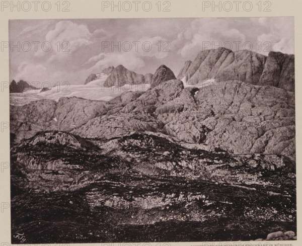 Das Carls-Eisfeld von der Ochsenwieshöhe, View of the Hallstätter Glacier, page, photomechanical print, number: 'VIII.', photographer: Friedrich Simony, Salzburg (city), cliché maker: Friedrich Bruckmann, Vienna, publisher: Eduard Hölzel, c. 1879 - in or before 1889, Lower Austria, paper, collotype, photoprint, height 147 mm x width 187 mm, glacier, Hallstätter Gletscher, A monochrome landscape showing layered rocky terrain rising toward jagged mountain peaks, with textured rock faces and crevices in the foreground and midground, patches of lighter smooth surfaces suggesting snow or ice tucked between ridges, and a sky filled with soft, billowing clouds above the peaks.