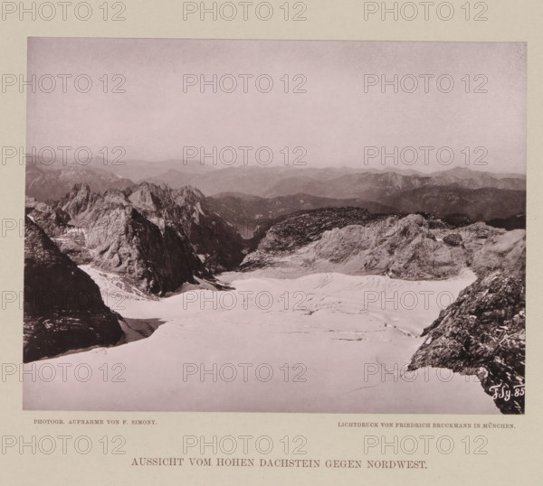 View from the Dachstein Mountains, Aussicht vom Hohen Dachstein gegen nordwest, page, photomechanical print, number: 'XII.', photographer: Friedrich Simony, Dachstein (Salzburg), cliché maker: Friedrich Bruckmann, Vienna, publisher: Eduard Hölzel, 1885, Lower Austria, paper, collotype, light print, height 141 mm x width 190 mm, mountain-top, peak, A wide sepia-toned mountain landscape showing a foreground of snow-covered slopes and rocky outcrops, jagged dark rock formations rising on the left and right edges, a central expanse of smooth pale snow with faint surface textures and tracks, a middle distance of rugged rocky ridges and cliffs with tonal variations, and a hazy layered range of distant mountains under a pale sky occupying the upper portion of the image.