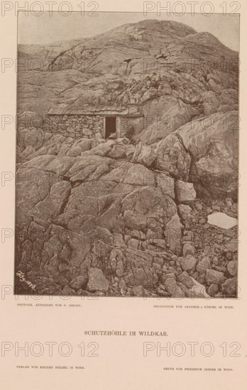 Schutzhöhle im Wildkar, Shelter on the Wildkarspitze, page, photomechanical print, number: 'XIV.', photographer: Friedrich Simony, Tirol, cliché maker: Angerer & Göschl, C., Vienna, publisher: Eduard Hölzel, 1876, Lower Austria, Tyrol, paper, autotypie, height 196 mm x width 154 mm, hut, cabin, lodge, mountain-top, peak, Wildkarspitze, A sepia-toned image showing a rocky mountainside with layered, weathered rock formations filling most of the frame and a low stone shelter built into the rock face with a small dark doorway and a simple roof, surrounded by uneven boulders and crevices, with steeper rock slopes rising behind the shelter and more broken rock and pebble-strewn ground in the foreground.