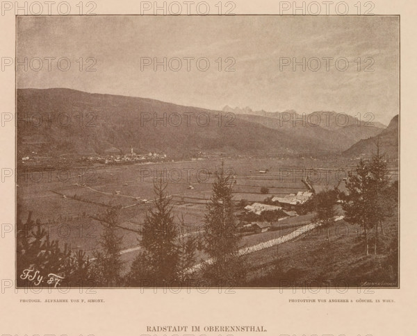 Radstadt im Oberennsthal, View of Radstadt, page, photomechanical print, number: 'XVI.', photographer: Friedrich Simony, Austria, cliché maker: Angerer & Göschl, C., Vienna, publisher: Eduard Hölzel, 1887, Lower Austria, paper, autotypie, height 140 mm x width 195 mm, city-view in general, 'veduta', Salzburg (city), Radstadt, A sepia-toned landscape photograph shows a wide valley with fields and scattered buildings, framed by distant mountains under a pale sky; trees and darker vegetation appear in the foreground, and a small cluster of structures including a tall steeple is visible near the valley center.