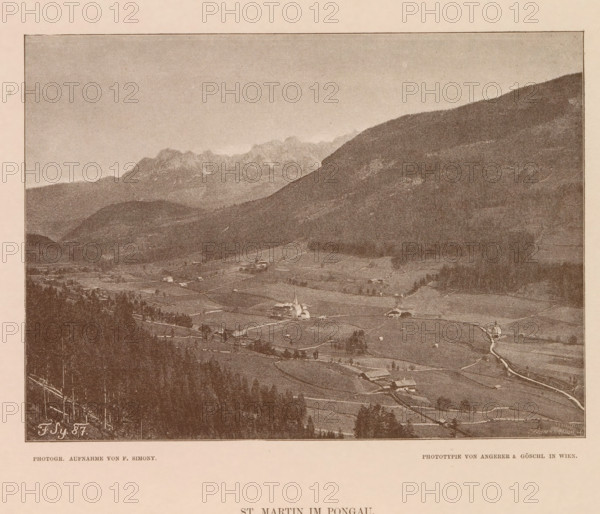 View of Sankt Martin am Tennengebirge, St. Martin im Pongau, page, photomechanical print, number: 'XVIII.', photographer: Friedrich Simony, Salzburg (city), cliché maker: Angerer & Göschl, C., Vienna, publisher: Eduard Hölzel, 1887, Lower Austria, paper, autotypie, height 142 mm x width 195 mm, city-view in general, 'veduta', Sankt Martin am Tennengebirge, A sepia-toned panoramic view showing a valley with fields and scattered buildings, a small church with a steeple near the center, winding roads and paths linking houses and farms, clusters of trees and wooded slopes in the foreground, a large rounded hillside rising on the right, distant jagged mountain peaks along the horizon, and a wide pale sky above.