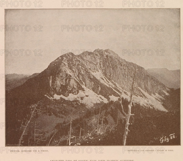 View of a mountain peak in the Dachstein Mountains, Ansicht des Blassen von der Hohen Scheibe, page, photomechanical print, number: 'XX.', photographer: Friedrich Simony, Dachstein (Salzburg), cliché maker: Angerer & Göschl, C., Vienna, publisher: Eduard Hölzel, 1886, Lower Austria, paper, autotypie, height 159 mm x width 200 mm, mountain-top, peak, A sepia-toned image showing a jagged mountain ridge with rocky faces and patches of snow, a foreground with bare tree trunks and branches, a darker wooded slope below the mountain, and a wide pale sky above, all framed by a thin border.