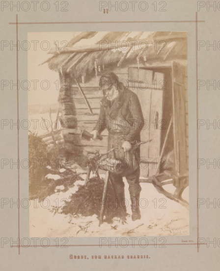 Photo reproduction of a painting by Karl Emanuel Jansson, depicting an old man chopping wood from spruce, Gubbe, som hackar granris, photograph, reproduction, page, inscription: 'Åland 1871', number: 'II', photographer: Daniel Nyblin, after painting by Karl Emanuel Jansson, c. 1871 - in or before 1880, paper, albumen print, albumendruk, height 176 mm x width 138 mm, picture, painting, woodcutting, woodcutter, forestry, old man, An aged man wearing a coat and cap stands outside a rustic wooden cabin with a thatched roof, holding an axe in one hand and a log in the other; snow covers the ground around him and clumps of brush and chopped wood are visible nearby, while the cabin shows a door with a handle and rough timber walls, and the scene is framed by a pale border with thin decorative lines.
