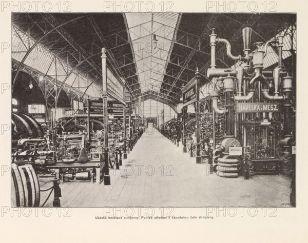 Ukázka instalace strojovny. Pohled stredem k západnimu celu strojovny, View of the engine room at the Výstavište in Prague, page, photomechanical print, Výstavište, cliché maker: Carl Bellmann, Prague, c. 1888 - in or before 1893, photographer, paper, autotypie, height 178 mm x width 258 mm, interior, representation of a building, machines, parts of machines, tools and appliances, A large indoor industrial hall with a high arched roof and a central skylight running along its length, flanked on both sides by rows of heavy machinery and metal equipment, including tall vertical pipes, coiled tubes, and cylindrical vessels clustered on the right and various engines, flywheels, and mechanical components arranged on the left, all set on a wooden plank floor with a clear central aisle leading toward a distant doorway, supported by metal columns and trussed beams that form curved arches and latticework overhead, with hanging light fixtures visible beneath the roof and small decorative finials ...