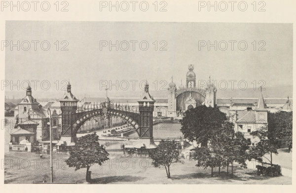 Pohled na výstavu od jihu v dobe zahájeni, View of the Výstavište in Prague, page, photomechanical print, Prague, cliché maker: Carl Bellmann, c. 1888 - in or before 1893, photographer, paper, autotypie, height 152 mm x width 264 mm, temporary exhibition, 'Salon', façade (of house or building), Výstavište, A wide view shows an ornate entrance complex with tall decorative towers and an arched iron bridge spanning between two larger towers, detailed with circular motifs and railings. In the foreground there are several trees with full canopies, a grassy area, and a few small structures and lampposts. Behind the bridge an elaborate central building features domed cupolas, sculptural decorations, and a large arched portal flanked by towers with ornamental tops. Flanking buildings with pitched roofs, turrets, and chimneys extend to either side, and a carriage sits near the lower right corner. The sky above is pale and empty.