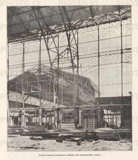 Vnitrek zelezné konstrukce ustredni sine prumysloveho paláce, Interior of the Industrial Palace under construction in Prague, page, photomechanical print, Výstavište, cliché maker: Carl Bellmann, Prague, c. 1888 - in or before 1893, photographer, paper, autotypie, height 220 mm x width 190 mm, building-site, A large interior space dominated by a tall iron framework and glass walls with arched window patterns, showing vertical and horizontal metal beams, lattice trusses, and curved supports; an elevated roof structure with visible rafters and intricate metalwork stretches across the top; beneath the iron skeleton there are platforms, scaffolding, and partial brick or stone walls with openings and columns; the floor area contains scattered long wooden beams and construction debris, and a small wheeled cart is visible among the materials; overall the scene shows an industrial building under construction with exposed structural elements and large glazed panels.