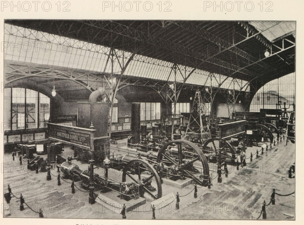 Pohled do strojovny. Výstava akciové strojirny drive Breitfeld, Danek a spol. v Katrine, Interior of a machine room with an exhibition of machines by Breitfeld and Danek, page, photomechanical print, Prague, cliché maker: Carl Bellmann, c. 1890 - in or before 1895, photographer, paper, autotypie, height 176 mm x width 258 mm, interior, representation of a building, machines, parts of machines, tools and appliances, A large indoor industrial hall with a high vaulted roof supported by metal trusses and arched iron columns, long rows of windows along the upper walls, hanging pendant lights, and a polished floor. Inside the hall are multiple large mechanical machines with prominent flywheels, pistons, and belts arranged on raised bases and connected by chains to low posts, with several decorative posts and ropes forming barriers around the exhibits. There are tall framed panels and a raised platform structure near one side, an overhead duct or pipe rising above a rectangular enclosure, and...