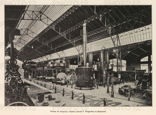 Interior of an engine room with an exhibition of Skoda, Pohled do strojovny. Výstava závodu E. Skody v Plzni, page, photomechanical print, Prague, cliché maker: Carl Bellmann, c. 1890 - in or before 1895, photographer, paper, autotypie, height 176 mm x width 258 mm, interior, representation of a building, machines, parts of machines, tools and appliances, The image shows the interior of a large industrial exhibition hall with a high iron and glass roof supported by slender arched metal columns and trussed beams; the floor area is filled with heavy machinery including tall cylindrical boilers, large gears, flywheels, and other engine components arranged behind short posts connected by chains, with display platforms and stairways; lantern-style lights hang from the roof and large windows along the side wall admit light; in the foreground there is a stack of circular metal parts and various scattered smaller components on the floor, while further back are mounted machines and a tall verti...