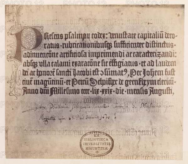 Photo reproduction of a page of a psalter, photograph, reproduction, page, number: '26', photographer: B. Erdmann, Mainz, printer (person): Johann Fust, c. 1867 - in or before 1872, printer (person), Rhineland-Palatinate, paper, albumen print, height 202 mm x width 231 mm, book, A large aged page with a decorative ornate initial occupying the top left, ornate flourishes along the left margin and a block of dark dense blackletter text filling the upper half of the sheet, beneath which there is faded handwriting in a lighter ink and a circular stamped oval seal toward the lower center, all on a stained, yellowed parchment background with spots and smudges.