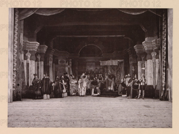 Christ before king Herod, page, photomechanical print, inscription: 'Gemeinde Oberammergau Passionsspiel 1890', photographer: Carl Stockmann, Oberammergau, cliché maker: anonymous, c. 1885 - in or before 1890, Bavaria, paper, collotype, photoprint, height 165 mm x width 226 mm, group of actors, troupe, actors on the stage, sometimes a gorgeous robe is brought (Luke 23:8-11), A wide stage set with tall decorative columns and an arched backdrop, draped curtains framing the scene, and a wooden floor in the foreground; a group of people in historical costumes stand and sit across the stage, wearing robes, capes, headdresses, and armor, some holding staffs, spears, banners, or other props, with a seated figure beneath a canopy toward the center and patterned tapestries or decorative panels behind them.