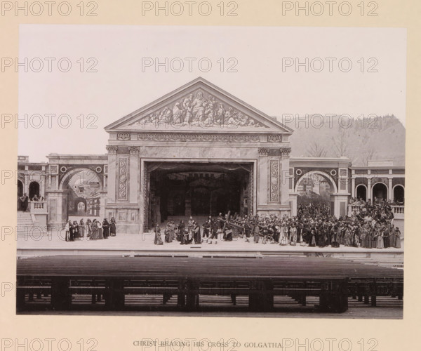 Christ bearing his cross to Golgatha, page, photomechanical print, inscription: 'Gemeinde Oberammergau Passionsspiel 1890', photographer: Carl Stockmann, Oberammergau, cliché maker: anonymous, c. 1885 - in or before 1890, Bavaria, paper, collotype, photoprint, height 167 mm x width 223 mm, group of actors, troupe, actors on the stage, from Pilate's palace to Golgotha: the procession to Calvary (Matthew 27:31-33, Mark 15:20-22, Luke 23:26-33, John 19:17), A wide stage set resembling a classical stone building with a central pediment decorated with carved figures and ornate frieze sits against a pale background with distant hills; a large open archway leads into a dark interior, flanked by tall columns with decorative panels and arches on either side. On the stage, many people in period costumes are arranged in clustered groups across the foreground, some standing on steps and balconies, others gathered near the central opening; several figures carry a large wooden beam across their shou...