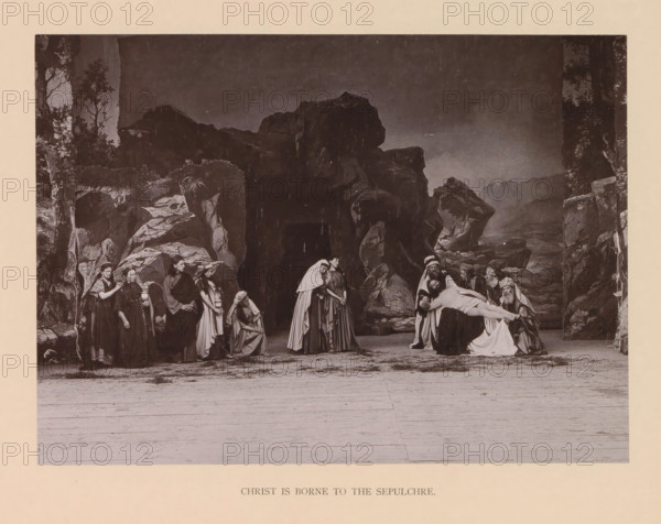 Christ is borne to the sepulchre, page, photomechanical print, inscription: 'Gemeinde Oberammergau Passionsspiel 1890', photographer: Carl Stockmann, Oberammergau, cliché maker: anonymous, c. 1885 - in or before 1890, Bavaria, paper, collotype, photoprint, height 168 mm x width 230 mm, Print after page 184., group of actors, troupe, actors on the stage, bearing of Christ's body to the grave, A sepia-toned stage scene shows a rocky backdrop with cliffs and sparse foliage framing a group of people dressed in historical robes and head coverings; on the left a line of figures stand and sit near rock formations, some with cloaks and shawls, one holding an object, several with downcast expressions, while toward the center two women in long garments stand close together and another kneels nearby; on the right a group of men with turbans and beards cradle a limp, draped body across their arms as others gather around, the foreground revealing a wide wooden stage floor and the entire composition...
