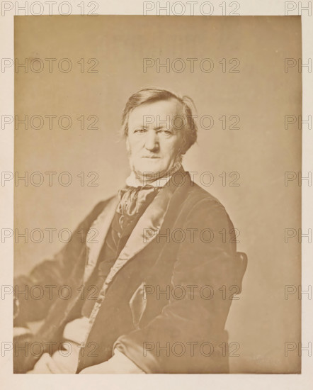 Portrait of Richard Wagner, photograph, page, photographer: Franz Hanfstaengl, Munich, c. 1873 - 1883, Bavaria, paper, albumen print, height 220 mm x width 177 mm, Photo opposite title page., Person, Richard Wagner, composer, A sepia-toned portrait of an older man seated and facing forward, showing his head and upper torso; he has light-colored hair combed to the side and sideburns, a neutral facial expression, and is wearing a dark jacket with a shiny lapel over a vest and a tied scarf at the neck; a plain, softly textured backdrop fills the space behind him and the image has a wide margin around the portrait.