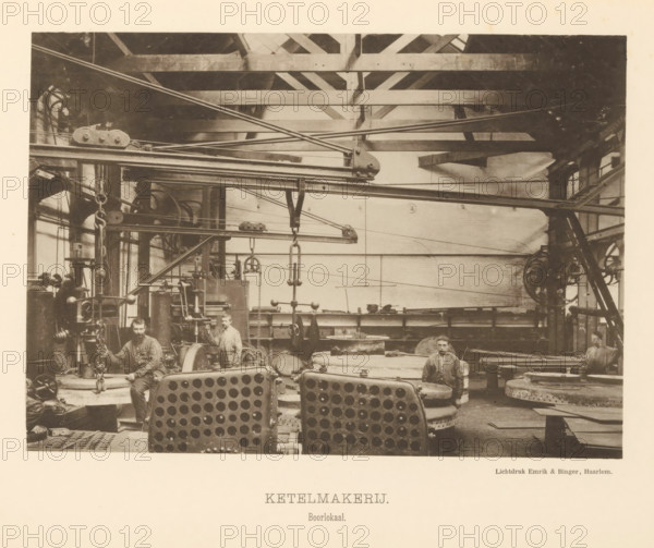 Boiler shop. Drilling room, Interior with employees of the boiler shop of the machine factory of Gebroeders Stork & Co, page, photomechanical print, number: 'No. 12.', Hengelo (Overijssel), maker: Emrik & Binger, Haarlem, c. 1884 - in or before 1894, photographer, paper, collotype, photogravure, height 152 mm x width 217 mm, factory-building, factory-interior, machine shop, A sepia-toned industrial interior shows large metal machinery, beams, pulleys, and overhead rods stretching across the space, with circular and perforated metal components in the foreground and heavy chains and hooks hanging from suspended fixtures; three men in work clothes are positioned among the equipment, two standing and one seated, each near different machines and parts, with visible gear wheels, cylinders, and workbenches around them; the ceiling structure consists of wooden trusses and beams, and windows and brick walls are visible at the sides and back, while various round metal plates and stacked componen...