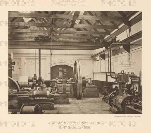 Anniversary Exhibition. 9-17 September 1893, Anniversary exhibition with steam boilers for the 25th anniversary of the machine factory of Gebroeders Stork & Co, page, photomechanical print, number: 'No. 15.', Hengelo (Overijssel), maker: Emrik & Binger, Haarlem, c. 1893-09-09 - in or before 1893-09-17, photographer, paper, collotype, photogravure, height 162 mm x width 211 mm, factory-interior, machine shop, exhibition, show, A sepia-toned interior view of a workshop showing wooden roof trusses and beams across the ceiling, a large horizontal metal girder with pulleys and chains suspended from it, and a variety of industrial machinery and mechanical equipment arranged on brick and concrete supports across the floor; a large flywheel and wheel with spokes are visible, along with pipes, belts, motors, and control components, and a pair of tall arched doors with slatted panels sit against the rear wall, flanked by brickwork and plastered walls with windows on one side.