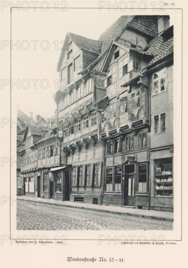 Exterior of buildings at Wendenstraße 12 and 14 in Braunschweig, Wendenstraße No. 12-14, Braunschweig's Baudenkmäler, page, photomechanical print, number: 'No. 15.', photographer: J. Schombardt, Braunschweig, cliché maker: Römmler & Jonas, Dresden, publisher: Benno und Wilhelm Danert Goeritz, 1892, J. Schombardt, Römmler & Jonas, Benno und Wilhelm Danert Goeritz, photographer, cliché maker, publisher, Lower Saxony, Saxony, paper, collotype, photoprint, height 148 mm x width 108 mm, street, facade (or house or building), A narrow cobblestone street lined with a row of tall, timber-framed buildings with overhanging upper stories and steep, tiled roofs, featuring multiple windows of various sizes and styles, some with small panes and some with shutters, ornate wooden carvings and decorative fan-shaped motifs beneath several windows, visible shopfronts at street level with display windows showing dishes and other items, a doorway with a hanging sign and a small awning, downspouts and expos...
