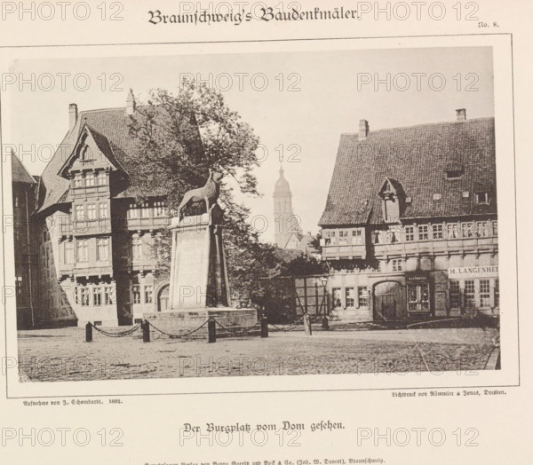 Der Burgplatz vom Dom gesehen, Burgplatz te Braunschweig, Braunschweig's Baudenkmäler, page, photomechanical print, number: 'No. 8.', photographer: J. Schombardt, Burgplatz (Braunschweig), cliché maker: Römmler & Jonas, Dresden, publisher: Benno und Wilhelm Danert Goeritz, Braunschweig, c. 1892, J. Schombardt, Römmler & Jonas, Benno und Wilhelm Danert Goeritz, photographer, cliché maker, publisher, Lower Saxony, Saxony, paper, collotype, photoprint, height 105 mm x width 160 mm, village square, Place, A sepia-toned scene of a town square showing ornate timber-framed buildings with steep tiled roofs and decorative facades, a tall tree partially obscuring one building, a stone pedestal topped by a sculpted animal figure in front of the tree, a cobbled ground in the foreground with short posts linked by chains, a narrow arched doorway and multiple windows on the buildings, a distant tower rising above the rooftops, and a lamppost near the base of the pedestal.
