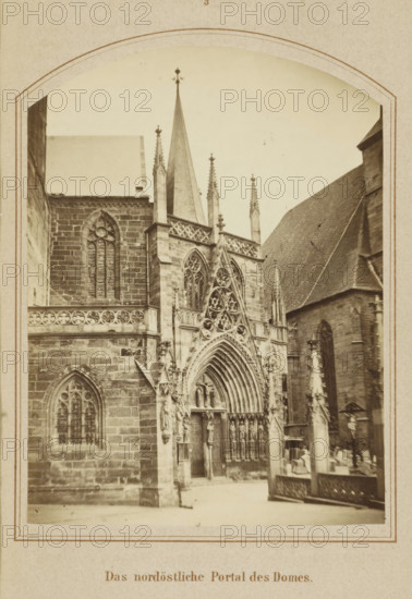 The northeastern portal of the cathedral, Northeastern entrance portal of the Cathedral of Erfurt, photograph, page, number: '3', Erfurt (city), c. 1858 - in or before 1868, photographer, Thuringia, paper, albumen print, height 125 mm x width 92 mm, Image opposite page 24., façade (of house or building), parts of church exterior and annexes: portal, Cathedral of Erfurt, A sepia-toned photograph of a gothic cathedral facade framed by a decorative arched border, showing pointed spires and ornate stonework. The central portal features a large pointed arch with concentric moldings, intricate tracery, and sculpted figures in niches flanking the doorway. Tall narrow lancet windows with tracery are set into the stone walls, and a steep roof plane rises to the right. Ornamental pinnacles and finials project above the parapet and along the roofline. In the foreground a low stone balustrade and a carved column or monument with decorative elements are visible, and a few indistinct figures appear ...