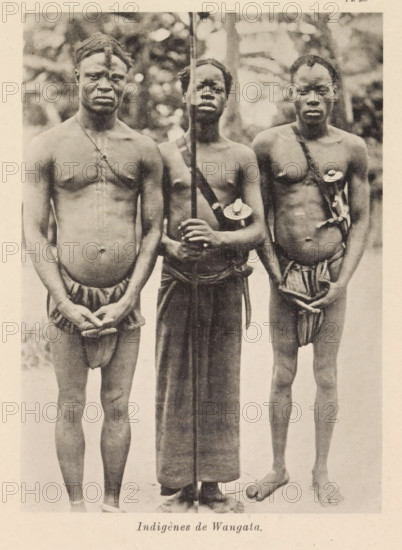 Indigènes de Wangata, Portrait of three men at Wangata, page, photomechanical print, number: 'Pl. 28.', photographer: Franz Thonner, Wangata, cliché maker: Stengel & Markert, Dresden, 1896, Saxony, paper, collotype, photoprint, height 161 mm x width 116 mm, adult man, casting weapons: spear, A sepia-toned photograph shows three shirtless men standing side by side facing the camera against a blurred outdoor background; the man on the left wears a headwrap and a narrow cloth around his waist with his hands clasped in front, a thin strap crosses his chest, and he has a rounded abdomen; the central man holds a long vertical staff with both hands, wears a long wrap from the waist down, and has a small round ornament attached to a strap across his chest; the man on the right has a narrow waist covering tied at the front, a strap diagonally across his chest with a circular ornament attached, and his hands are positioned near his groin; all three display neutral facial expressions and bare fee...